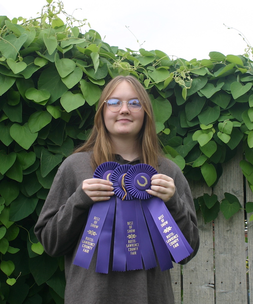 Casie holding her three purple Best of Show ribbons