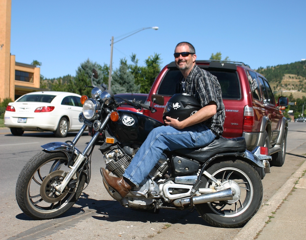 John Dale sitting on his motorcycle next to the curb in Spearfish, SD